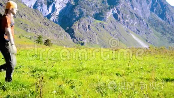 徒步旅行者带着背包在绿色的山地草地上行走。 夏季运动和娱乐理念。