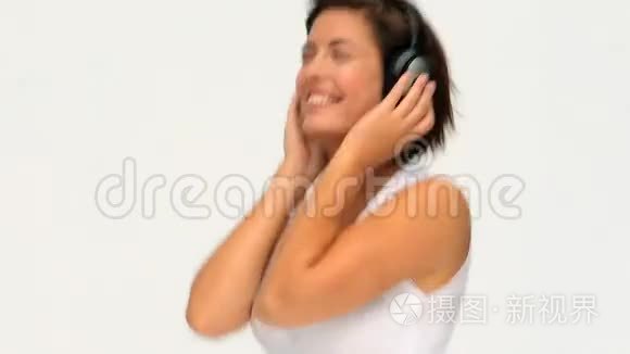 可爱的黑发女人带着耳机听音乐视频