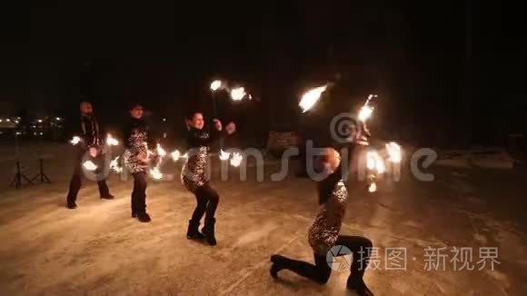 令人惊叹的部落火秀在夜幕下的冬天跳舞。 舞蹈团用火炬灯表演