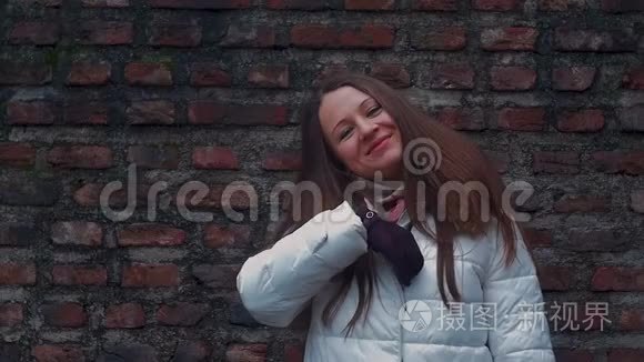 年轻女子微笑着面对砖墙背景视频