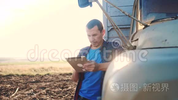 智慧农业。 男子农民司机站在卡车附近的数字平板电脑。 慢动作视频。 肖像商人