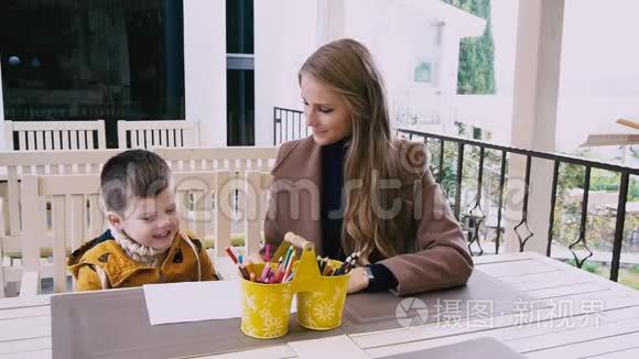母亲和年幼的儿子在餐桌旁画画