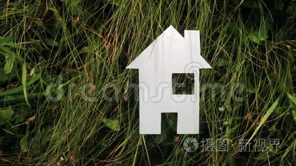 幸福家庭建设生活方式之家理念.. 纸房子矗立在大自然的绿草中。 象征生命生态