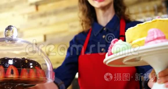 微笑的女服务员拿着蛋糕在柜台前的画像