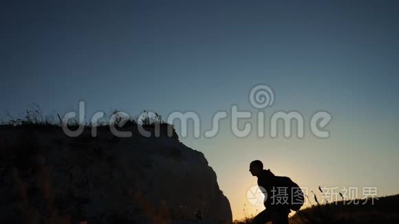 剪影游客登山者攀登一座山。 步行游客徒步旅行冒险登山者日落爬山。 慢慢慢慢