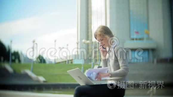 年轻的商务女性坐在台阶上，手提电脑在商务中心，阅读文件。