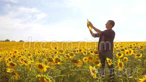 日落时分，农夫手捧一瓶葵花籽油. 慢动作视频。 农民农业塑料