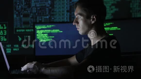 一位年轻的程序员在数据中心的一台电脑上工作的画像，里面装满了显示屏