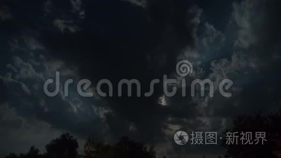 满月通过乌云和树木在夜空中移动。 时间流逝