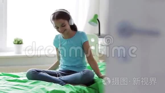 家里带着智能手机和耳机的快乐女孩