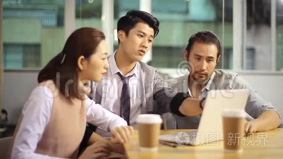 年轻的亚洲企业高管在办公室讨论业务