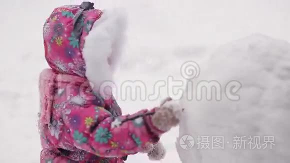 女孩在冬天的雪地里雕刻雪人。