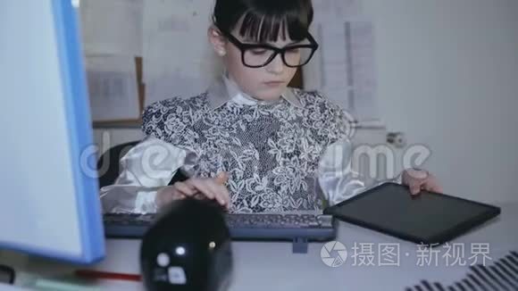 小女孩在办公室里用电脑和平板电脑工作。 4K