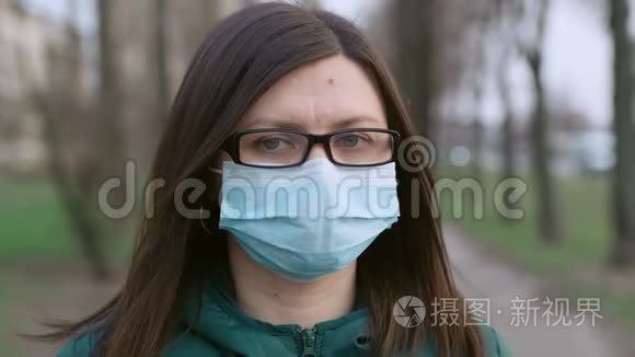 一个戴着眼镜和医用口罩的年轻女孩站在街上。