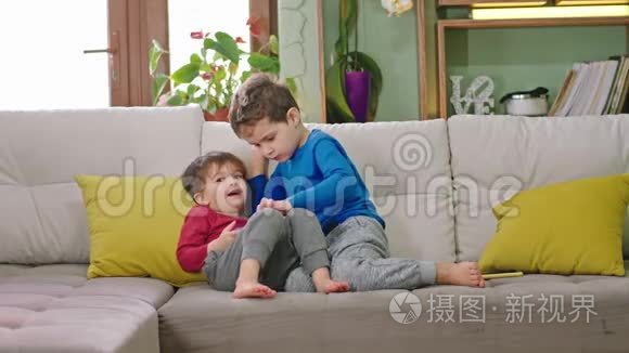 好朋友在沙发上，两个孩子在一起玩游戏玩得很开心，他们正在微笑
