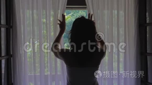 卧室里的女人早上打开窗帘和窗户