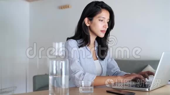 优雅的年轻女商人在办公室里用电脑工作时收到一条电话信息。