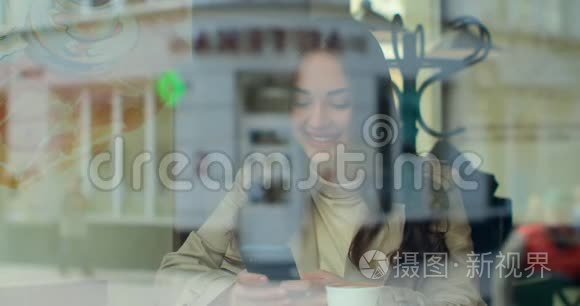 使用智能手机在咖啡馆喝咖啡的年轻女性在社交媒体上发短信，享受移动技术