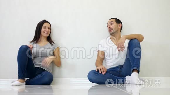 布鲁内特男女坐在白墙背景下，举起双手，表现出成长和成功。