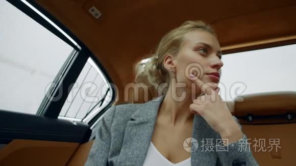 专注的女人坐在车上的肖像。 双足女孩在车后座思考