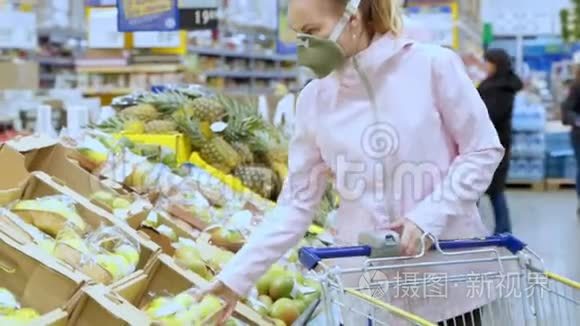 女人欧洲外观在一个保护性呼吸，医疗口罩在一个市场，一个商店。 选择蔬菜和水果