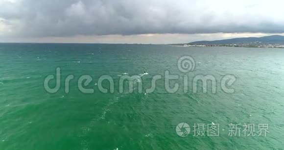 秋雨海，云，风.. 冲浪者在远处游泳。 从一架四翼直升机上