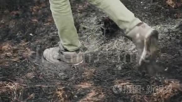 那家伙踩在烧焦的干草上。 腿的特写