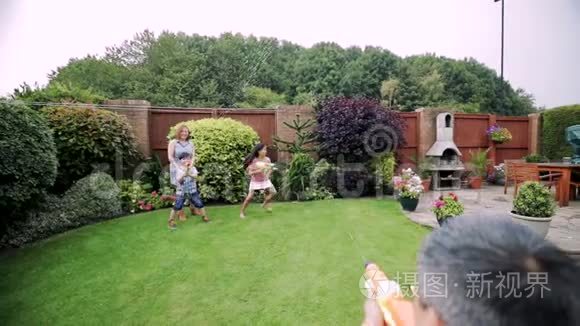 在花园里打水仗的家庭视频