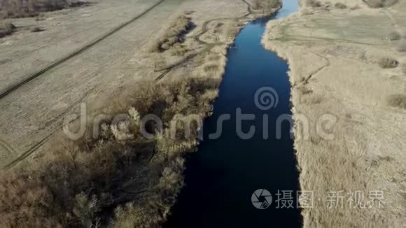 乡间宁静的河流。从上面看，这是一条神奇的河流，平静的河水坐落在大自然的一片春天的森林旁