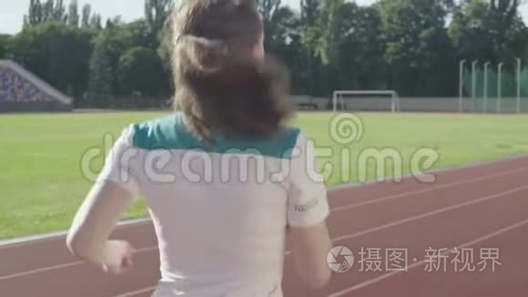 运动的年轻女孩在体育场跑步。 慢动作