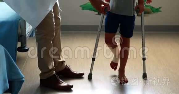 男医生协助受伤男孩拐杖行走视频