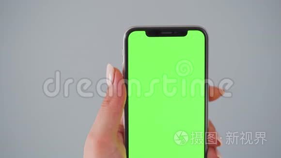 女性手使用智能手机，绿色屏幕在灰色背景。 铬键