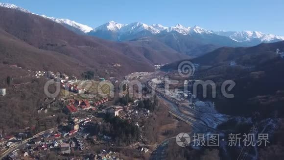 鸟瞰冬季奥地利村在山谷附近风景如画的阳光阿尔普山。 剪辑。 在路上飞过