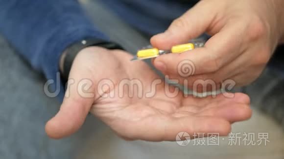 男人用手从水泡包里拿药丸。 特写男性手倒白橙圆片.. 手里拿着药剂丸。 氟