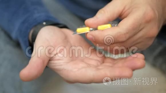 男人用手从水泡包里拿药丸。 特写男性手倒白橙圆片.. 手里拿着药剂丸。 氟