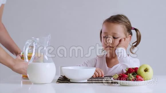 困倦的女孩开始吃她的玉米片和牛奶作为早餐。