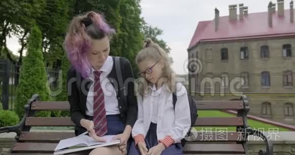 两个坐在长凳上的女学生，小学生和高中生。