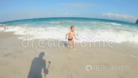 一个小男孩在热带海滩玩的慢镜头。 夏季概念