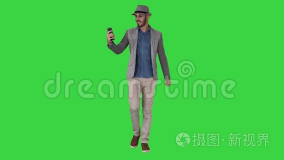 有魅力的男人穿着休闲服装，帽子，时髦的风格，记录Vlog或视频呼叫绿色屏幕，Chroma键。