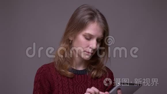 年轻的女学生打开平板电脑上的应用程序，并在灰色背景上演示绿色色度屏幕。