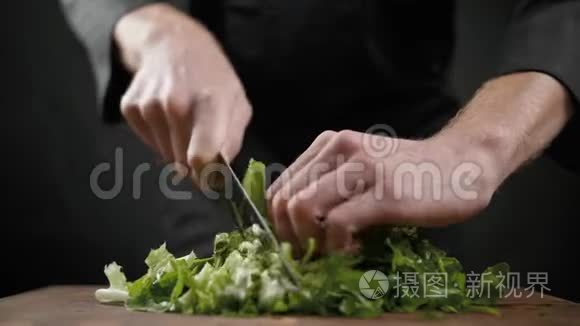 在黑色背景的木桌上为沙拉切下很多绿色生菜