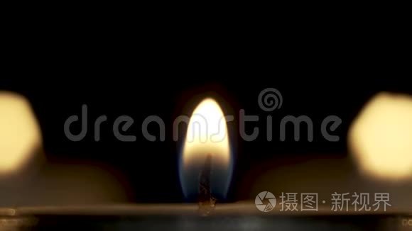 照相机在黑暗中燃烧的蜡烛的安静火焰上放大