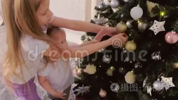两个孩子在家玩挂在圣诞树上的玩具。
