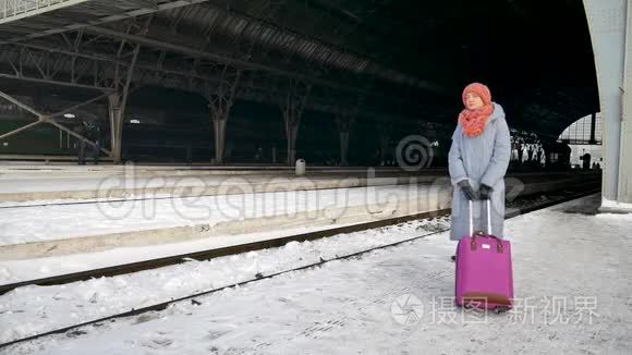 清晨，一个旅客妇女拿着紫色的行李站在火车站等待火车