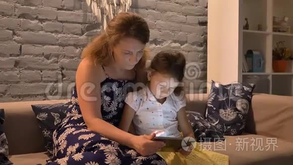 妈妈和小女儿坐在沙发上，用平板电脑，妈妈帮助孩子做小玩意，家庭观念，室内