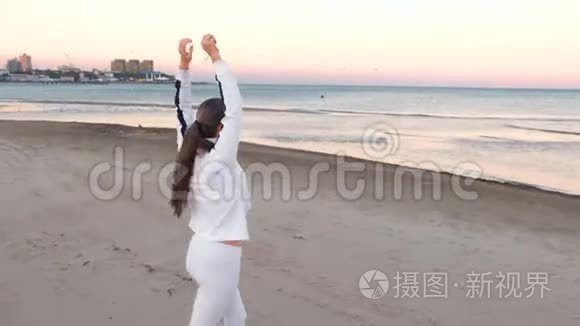 年轻女子正在做运动，以恢复呼吸在沙滩上日出在秋天，后景。