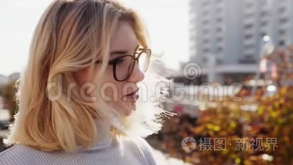 美丽的金发女郎戴着眼镜，望着阳光明媚的秋天城市