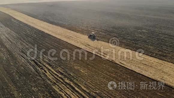 拖拉机农业单位在干燥的晴朗天气中进行耕作，种植褐色土壤
