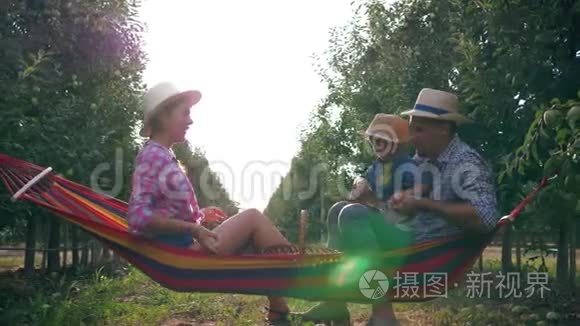 在温暖的夏日，一家人在美丽的花园里用草帽扔苹果，享受大自然