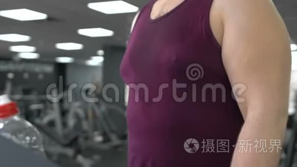 胖乎乎的男人在跑道上行走，在健身房跑步机上热身